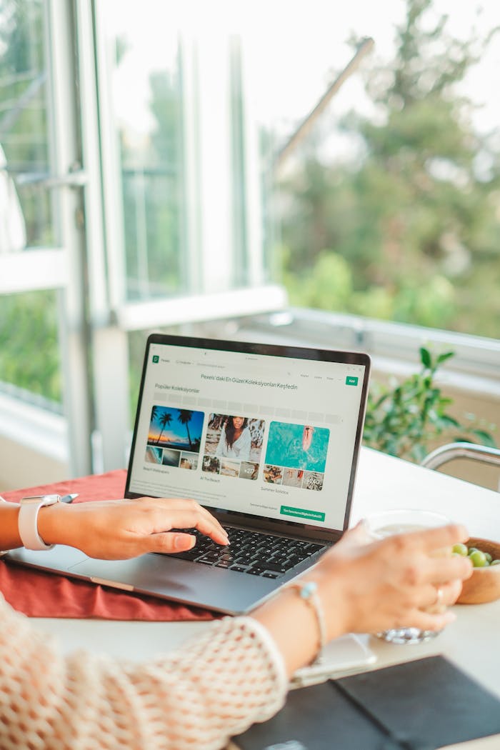 Services A person uses a laptop at a bright, sunlit home office desk, ideal for work-from-home themes.