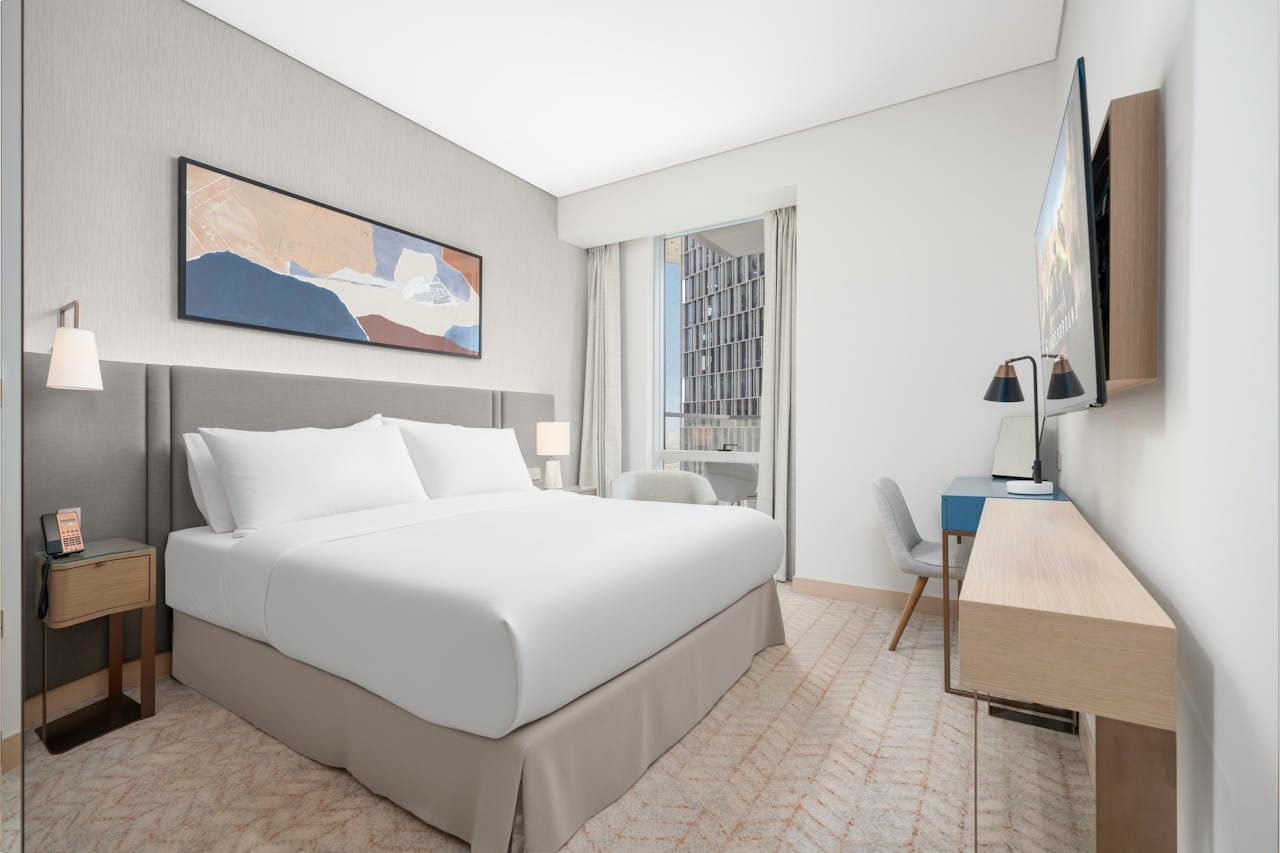 About Spacious and elegant modern hotel room featuring a king size bed, contemporary artwork, and a city view.